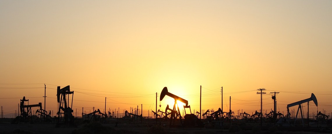 Bombas de petróleo em campo petrolífero durante o pôr do sol